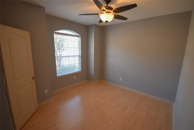 an empty room with windows and fan