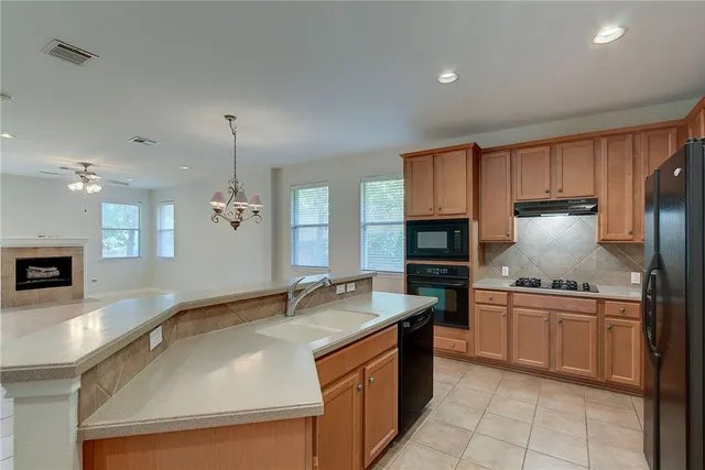 a kitchen with stainless steel appliances granite countertop a sink a stove and a wooden cabinets