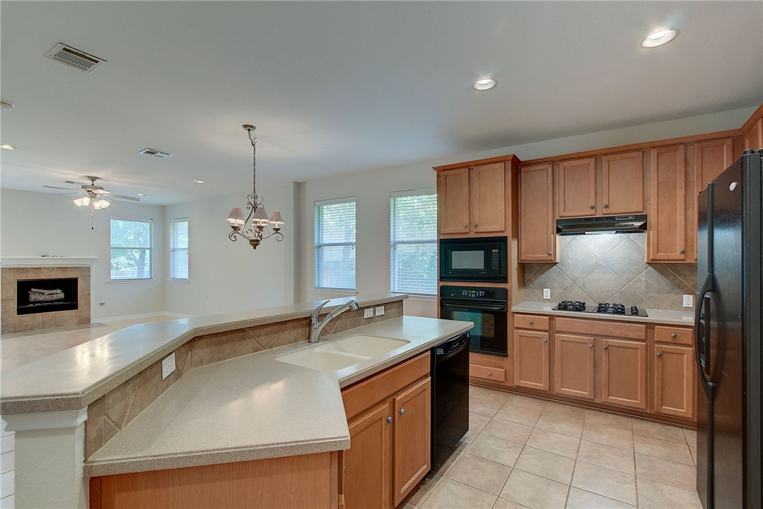 2993 Freemont Street Round Rock, TX 78681 - Photo 4 of 32 a kitchen with stainless steel appliances granite countertop a sink a stove and a wooden cabinets