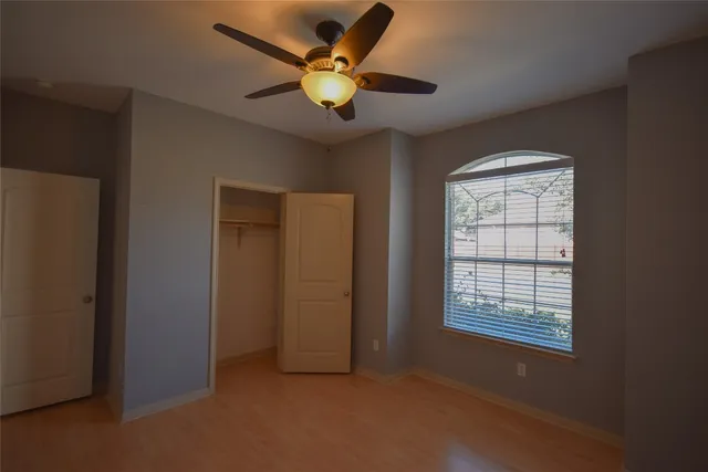 an empty room with windows and fan