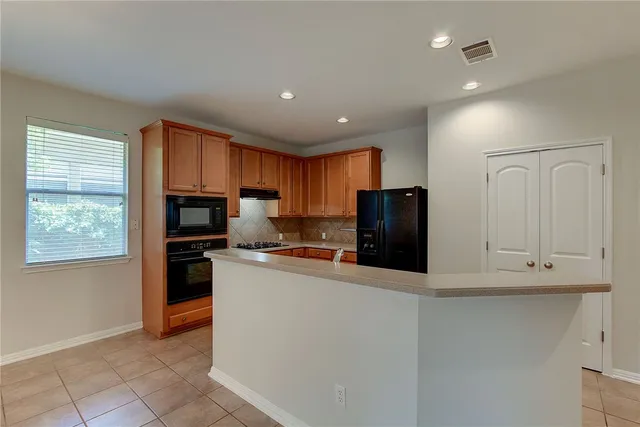 a kitchen with stainless steel appliances granite countertop a refrigerator and a stove top oven