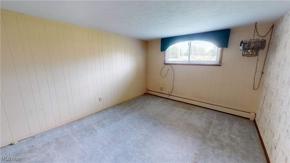 4444 Center Road Brunswick, OH 44212 - Photo 5 of 9 Carpeted empty room with baseboard heating, wooden walls, and a textured ceiling