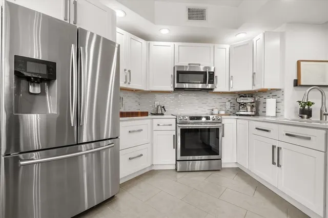 a kitchen with white cabinets and stainless steel appliances