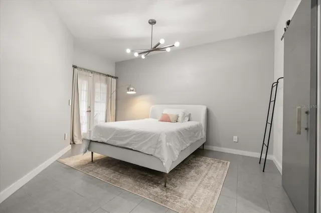 a bedroom with a large bed chandelier and a window