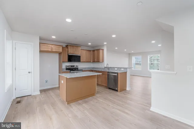 a kitchen with stainless steel appliances granite countertop a stove top oven a sink and a refrigerator