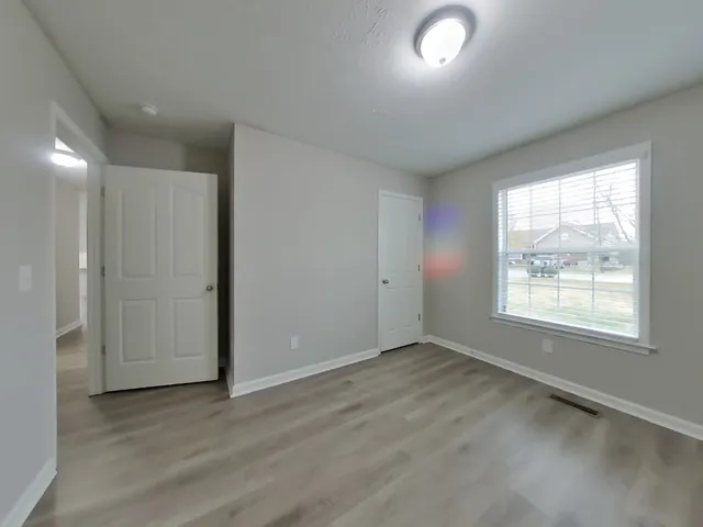 an empty room with wooden floor and windows