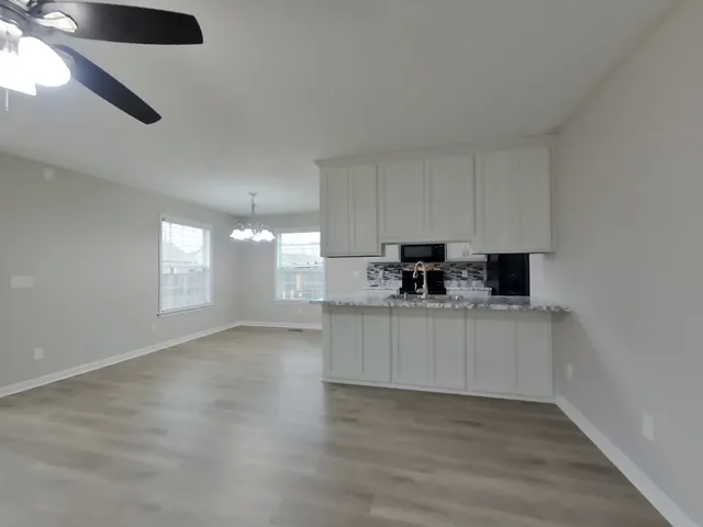 a view of a kitchen with a sink and dishwasher a refrigerator with wooden floor
