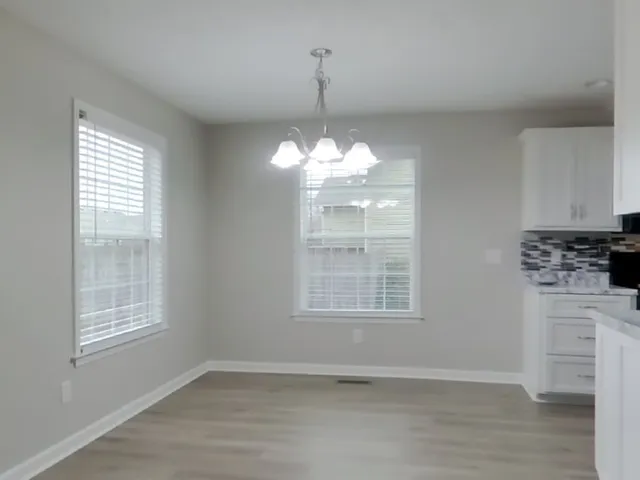 an empty room with wooden floor cabinets and windows