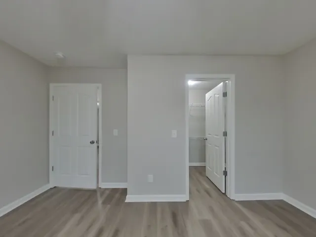 a view of an empty room with wooden floor and closet area
