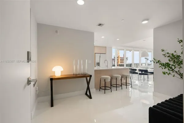a dining hall with stainless steel appliances a dining table chairs and couches with wooden floor