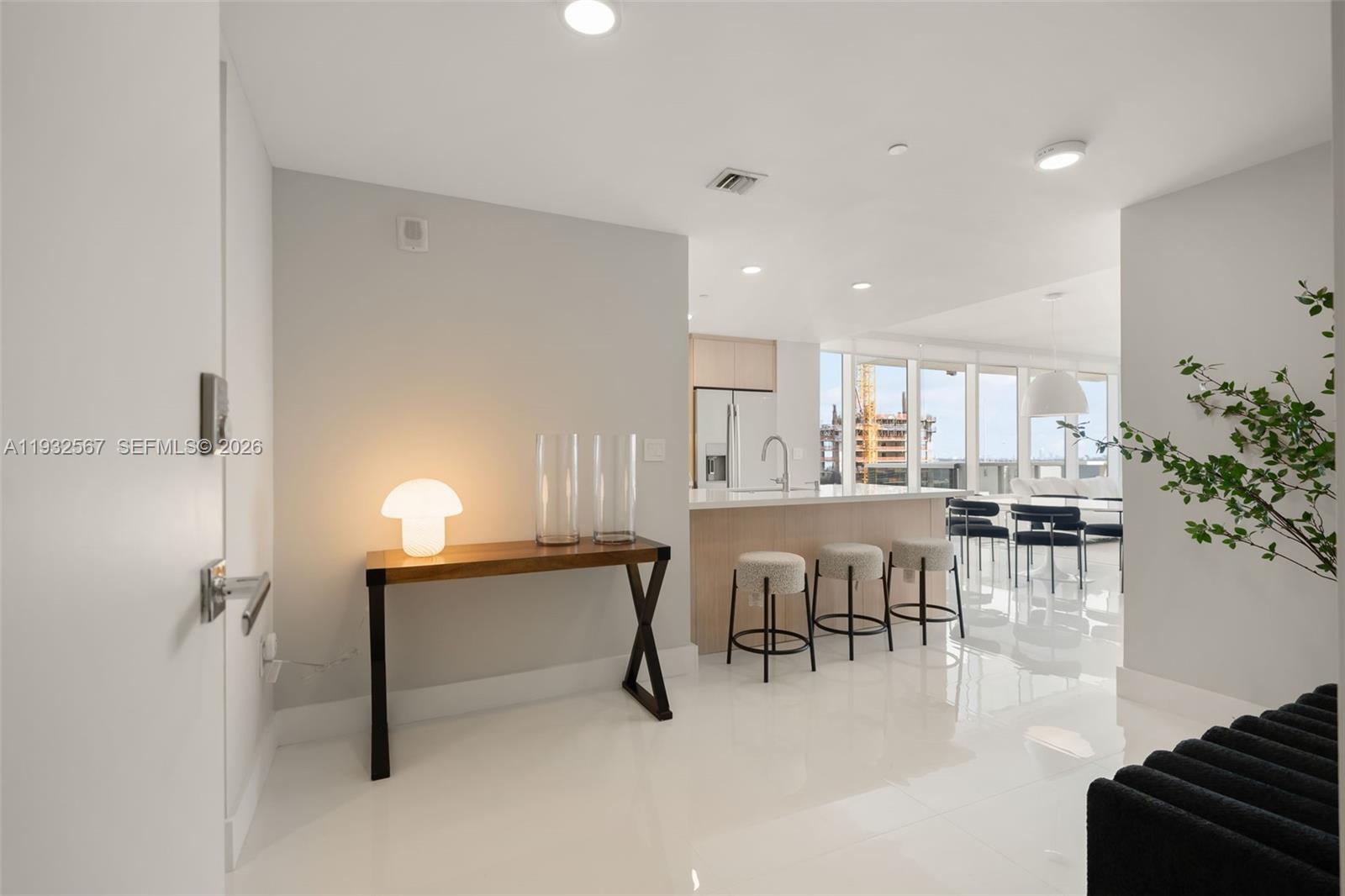 600 Northeast 27th Street, Unit 2401 Miami, FL 33137 - Photo 2 of 52 a dining hall with stainless steel appliances a dining table chairs and couches with wooden floor