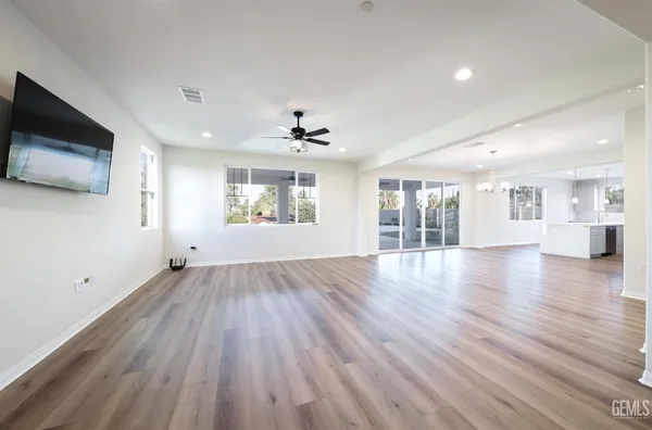 a large white kitchen with lots of counter space wooden floor and stainless steel appliances