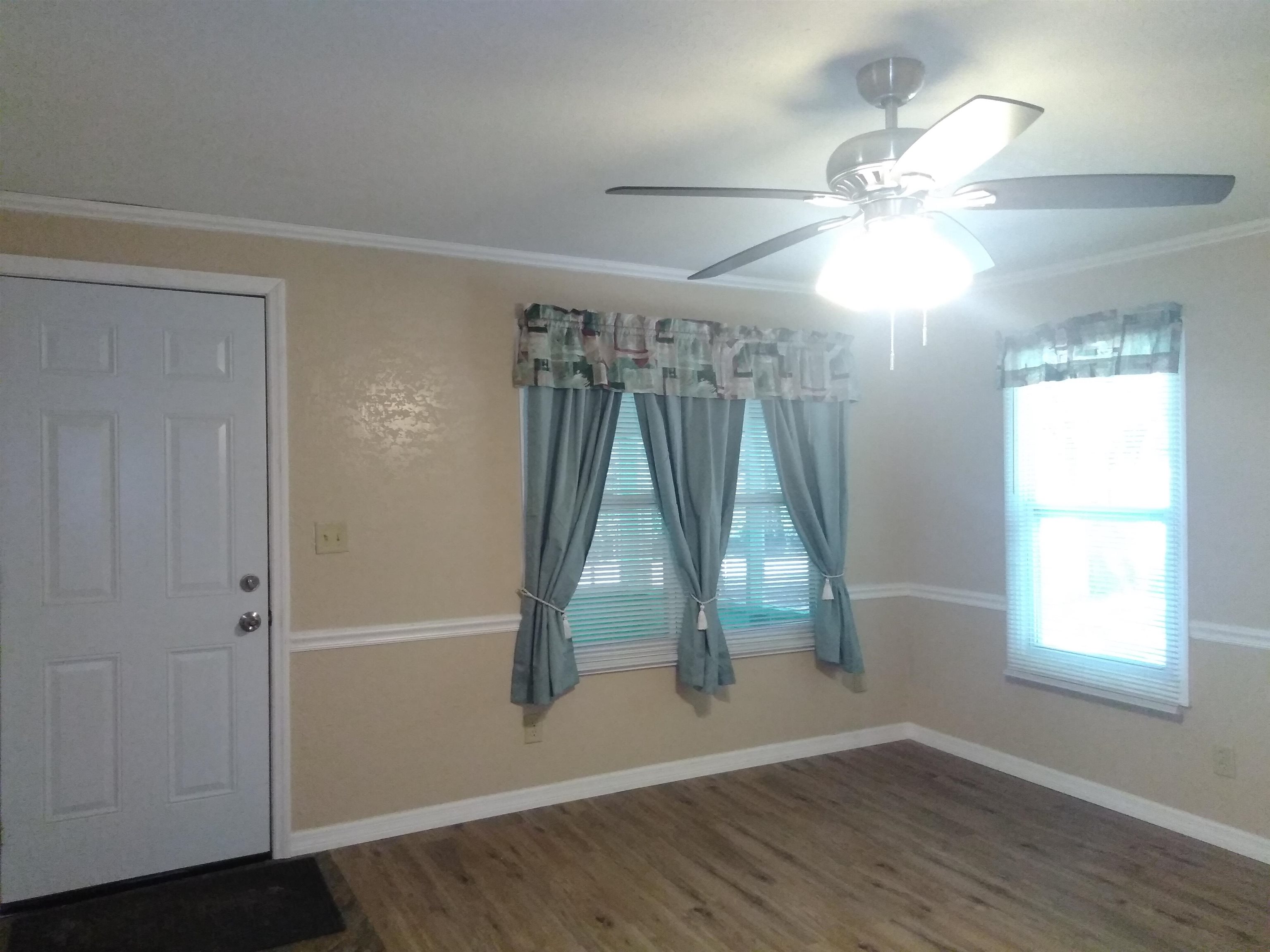 106 Putnam Loop Road Melrose, FL 32666 - Photo 3 of 28 an empty room with wooden floor fan and windows