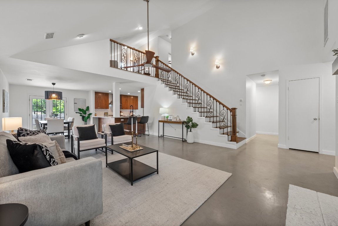a living room with furniture kitchen view and a wooden floor