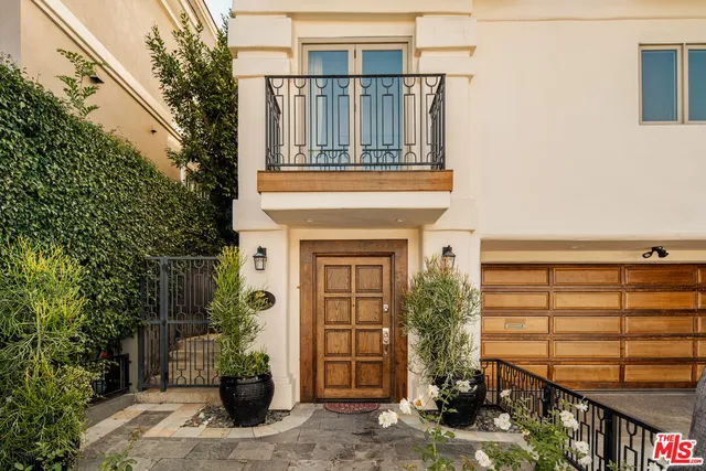 a front view of a house with glass windows and plants