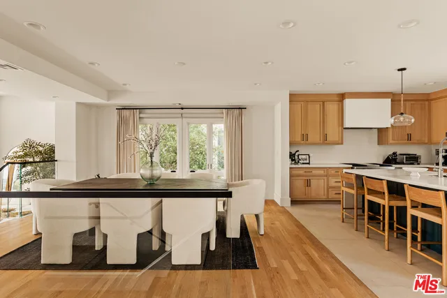 a kitchen with stainless steel appliances granite countertop a stove top oven a sink a dining table and chairs with wooden floor