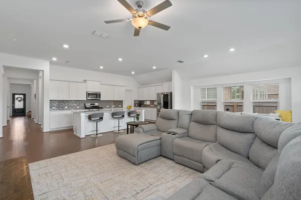 a living room with furniture kitchen view and a wooden floor