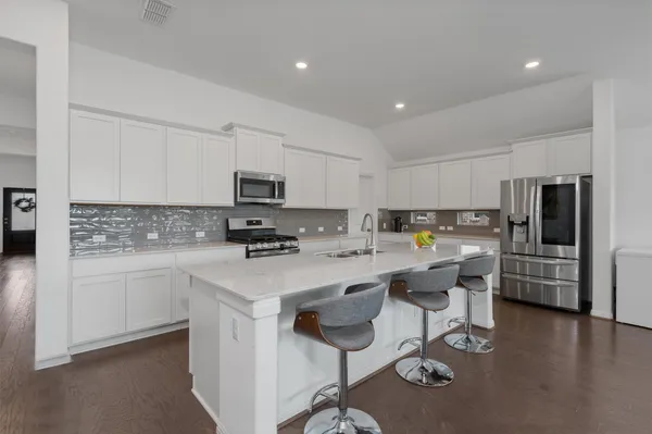 a kitchen with a sink a stove a refrigerator cabinets and a dining table