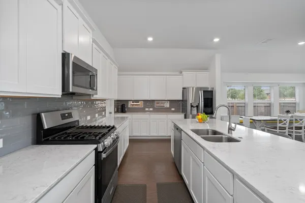 a kitchen with stainless steel appliances a sink a stove top oven a counter space and cabinets