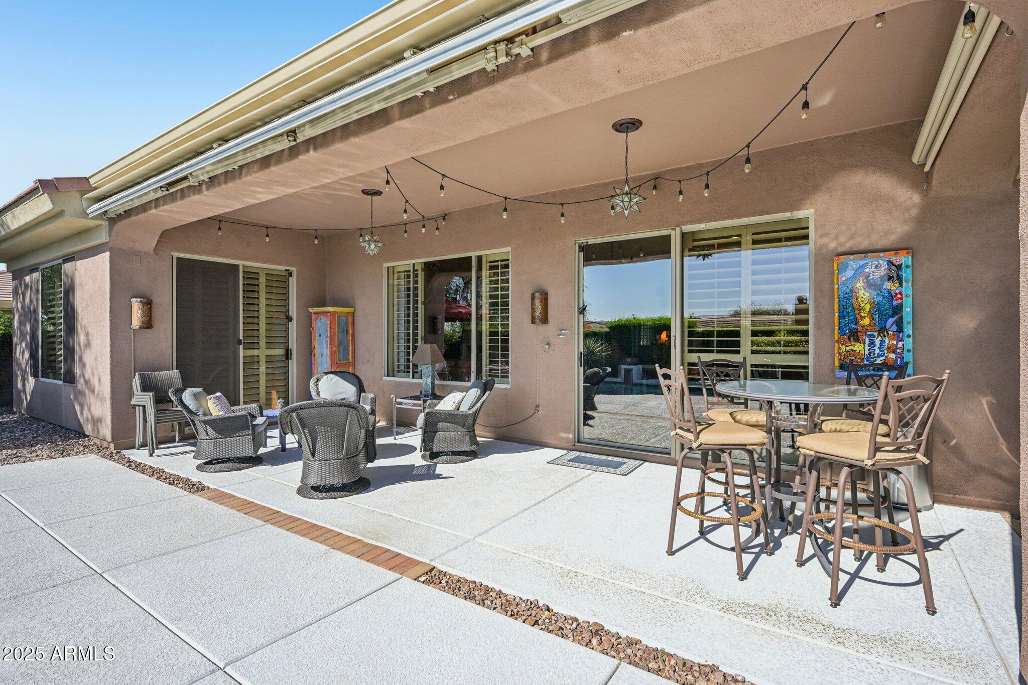 41725 North Golf Crest Road Anthem, AZ 85086 - Photo 9 of 60 a view of a patio with table and chairs potted plants and floor to ceiling window