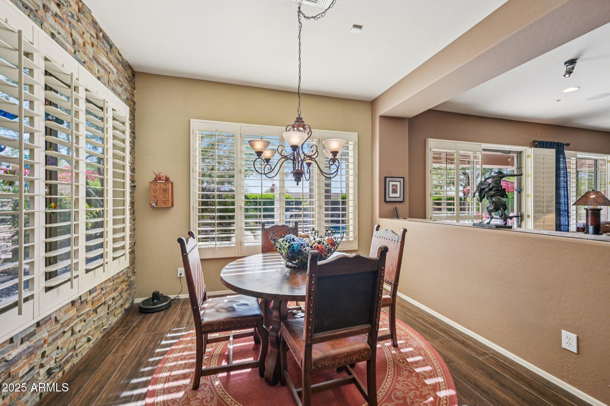 41725 North Golf Crest Road Anthem, AZ 85086 - Photo 18 of 60 a dining room with furniture a chandelier and wooden floor