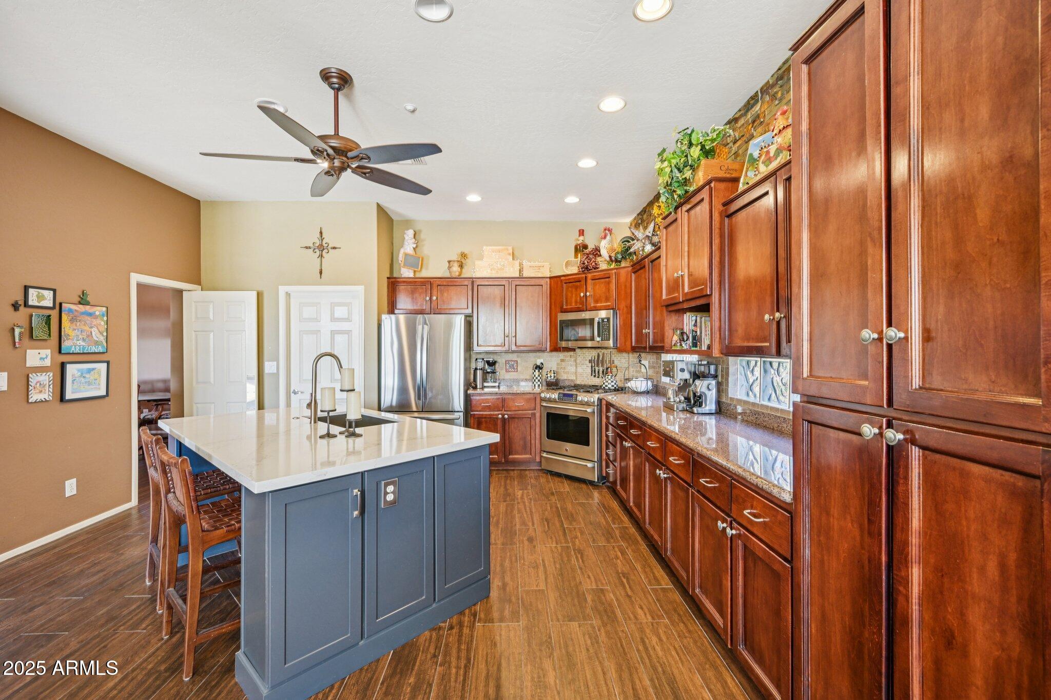 41725 North Golf Crest Road Anthem, AZ 85086 - Photo 40 of 60 a kitchen with stainless steel appliances a sink stove and wooden floor