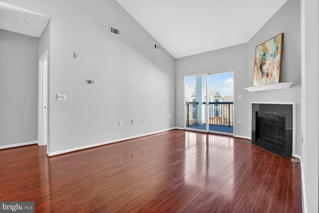 a view of empty room with wooden floor and fireplace