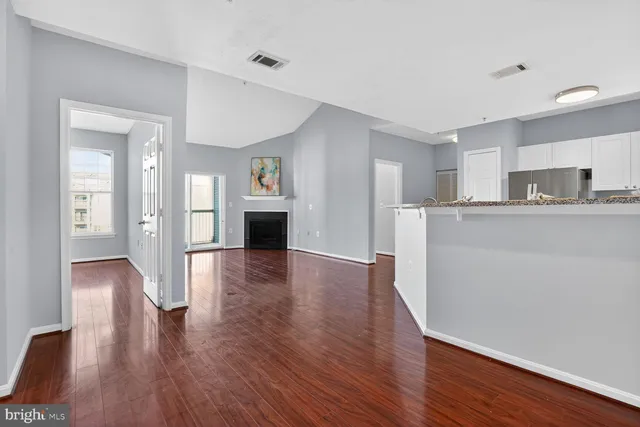 a view of a big room with wooden floor and a kitchen