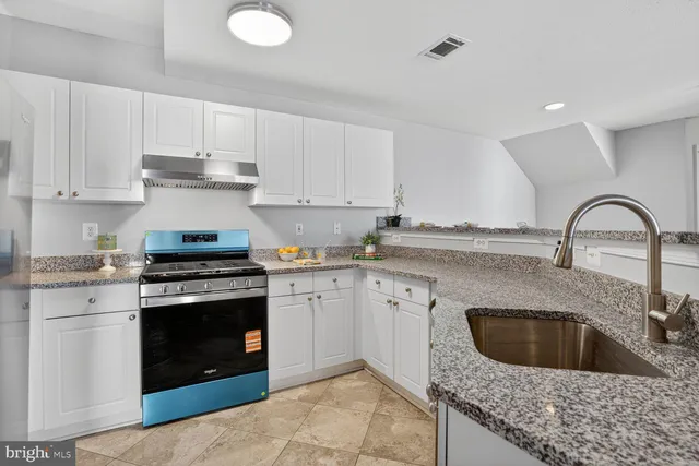 a kitchen with granite countertop a stove sink and cabinets