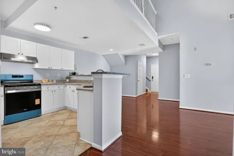 a kitchen with stainless steel appliances granite countertop a refrigerator a sink dishwasher and a stove with wooden floor