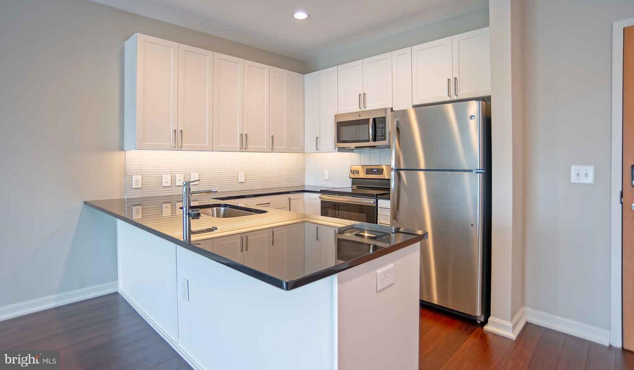 24 Cricket Avenue, Unit 2B604 Ardmore, PA 19003 - Photo 5 of 5 a kitchen with stainless steel appliances a refrigerator a sink a stove a microwave and island