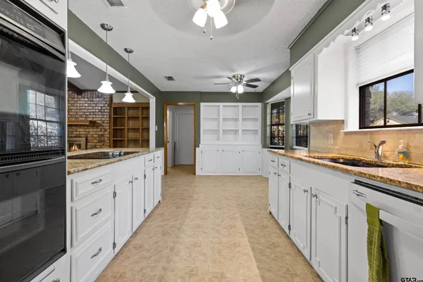 a large white kitchen with granite countertop a large window and white stainless steel appliances