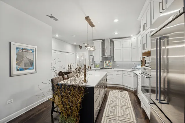 a view of a kitchen with kitchen island a counter space a sink appliances and cabinets
