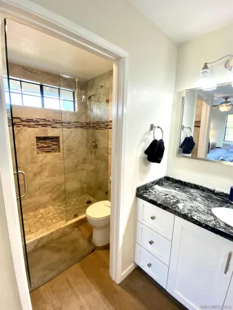 a bathroom with a granite countertop sink mirror vanity and toilet