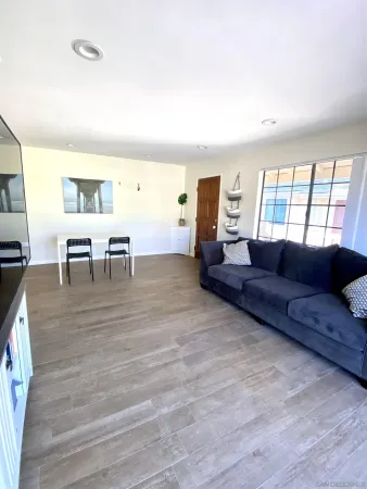 a living room with furniture and a dining table with wooden floor