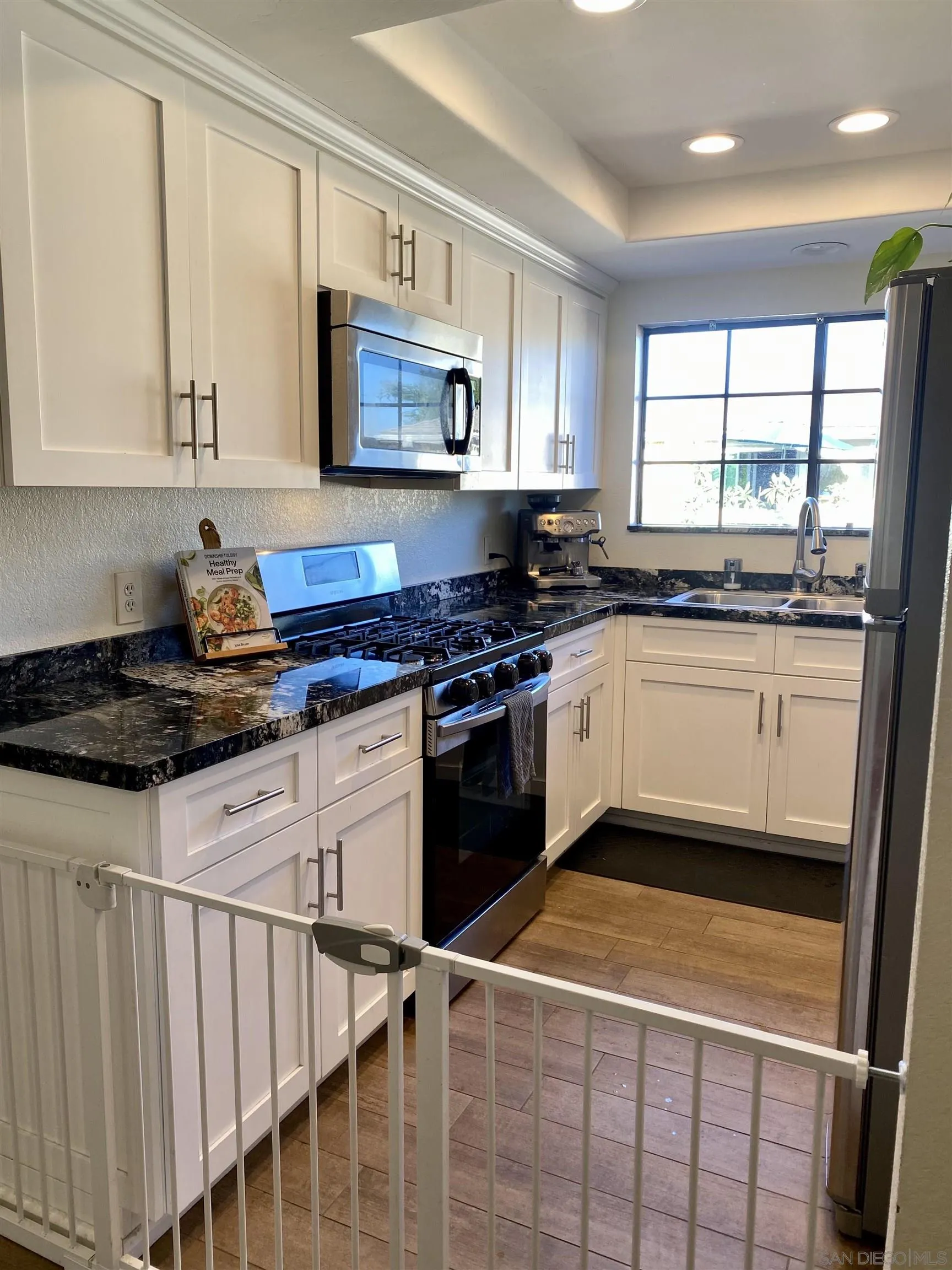 8834 Tamberly Lane, Unit D Santee, CA 92071 - Photo 7 of 28 a kitchen with stainless steel appliances granite countertop a stove a sink and white cabinets