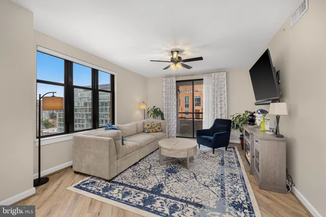 a living room with furniture a flat screen tv and a floor to ceiling window