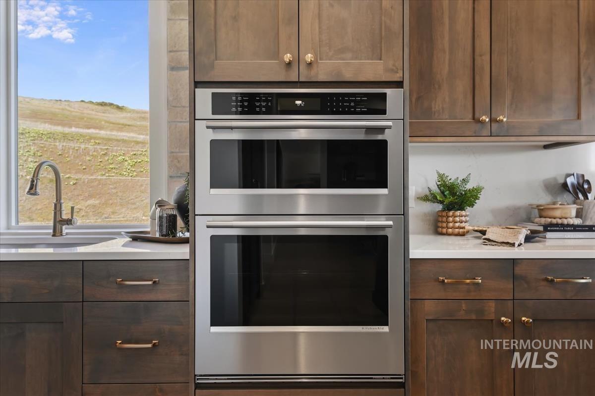 7615 Brown Way Eagle, ID 83714 - Photo 19 of 43 Kitchen featuring stainless steel double wall ovens, wood-finish cabinetry with brass hardware, and light-toned countertops
