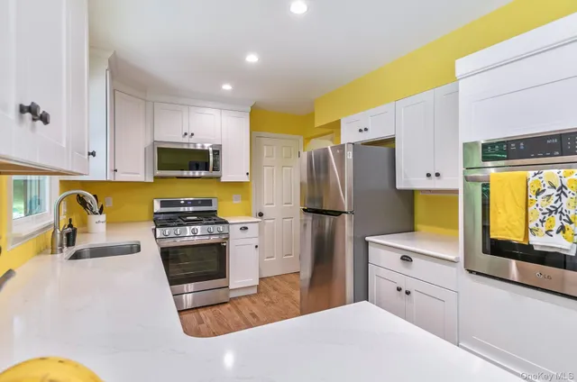a kitchen with stainless steel appliances a stove a refrigerator a sink a stove and white cabinets