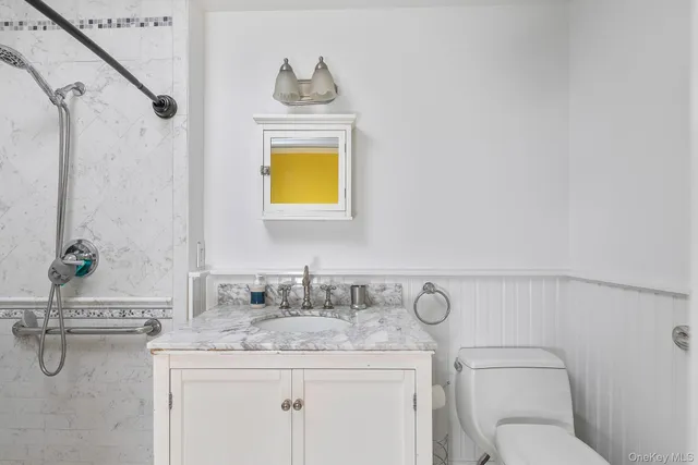 a bathroom with a granite countertop toilet sink and mirror