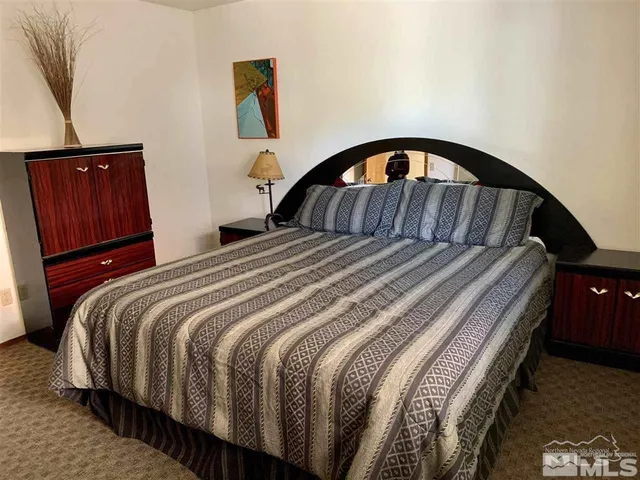 a bedroom with a bed a dresser and wooden floor