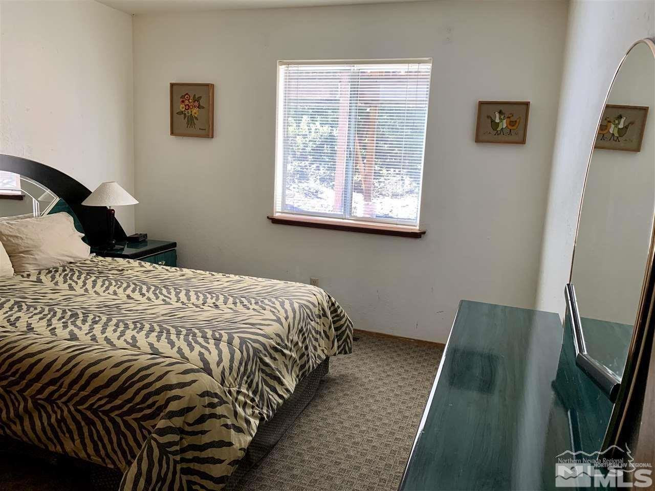 424 Quaking Aspen Lane, Unit B Stateline, NV 89449 - Photo 27 of 30 a bedroom with a bed a mirror and a window
