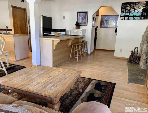 a living room with stainless steel appliances kitchen island granite countertop furniture and a wooden floor
