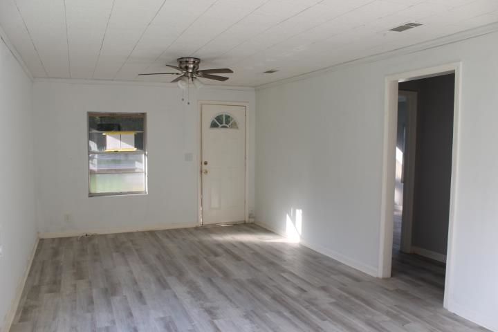875 Woodrow Street Silsbee, TX 77656 - Photo 11 of 30 an empty room with wooden floor chandelier fan and windows