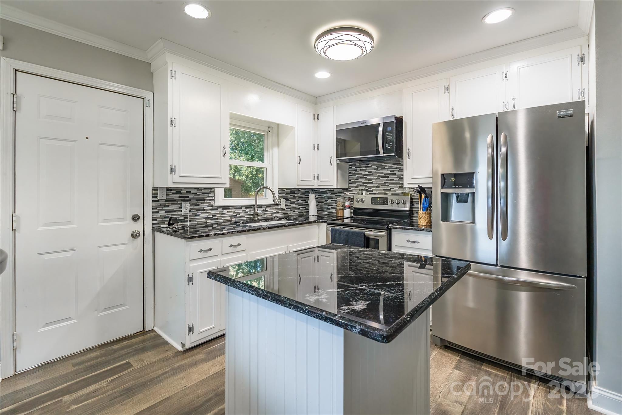 111 Berry Street Chester, SC 29706 - Photo 5 of 23 a kitchen with stainless steel appliances granite countertop a refrigerator a stove and a sink with wooden floor