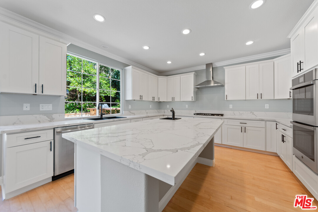 149 Laurel Ridge Drive Simi Valley, CA 93065 - Photo 19 of 53 a large kitchen with kitchen island granite countertop a stove a sink a refrigerator and white cabinets with wooden floor