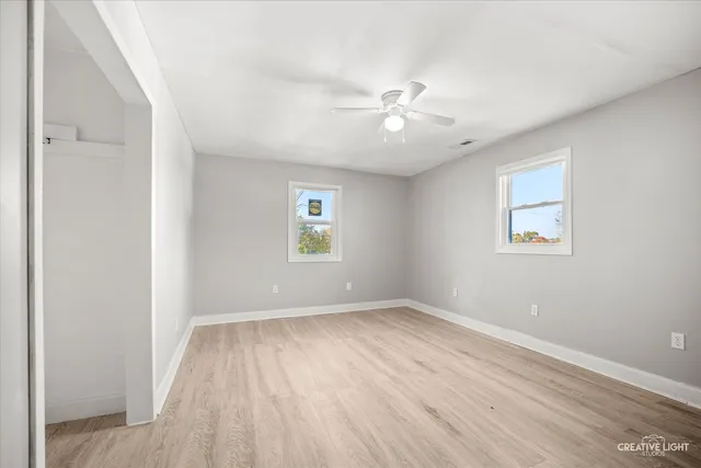 a view of empty room with wooden floor and fan