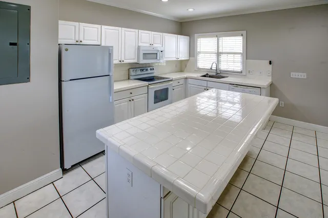 a kitchen with a white cabinets appliances and a window