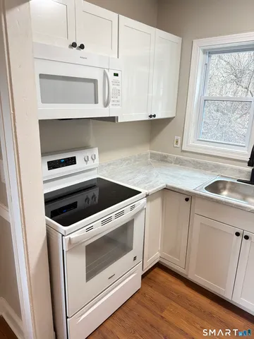 a kitchen with granite countertop white cabinets and white appliances