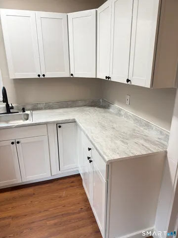 a kitchen with granite countertop white cabinets and sink